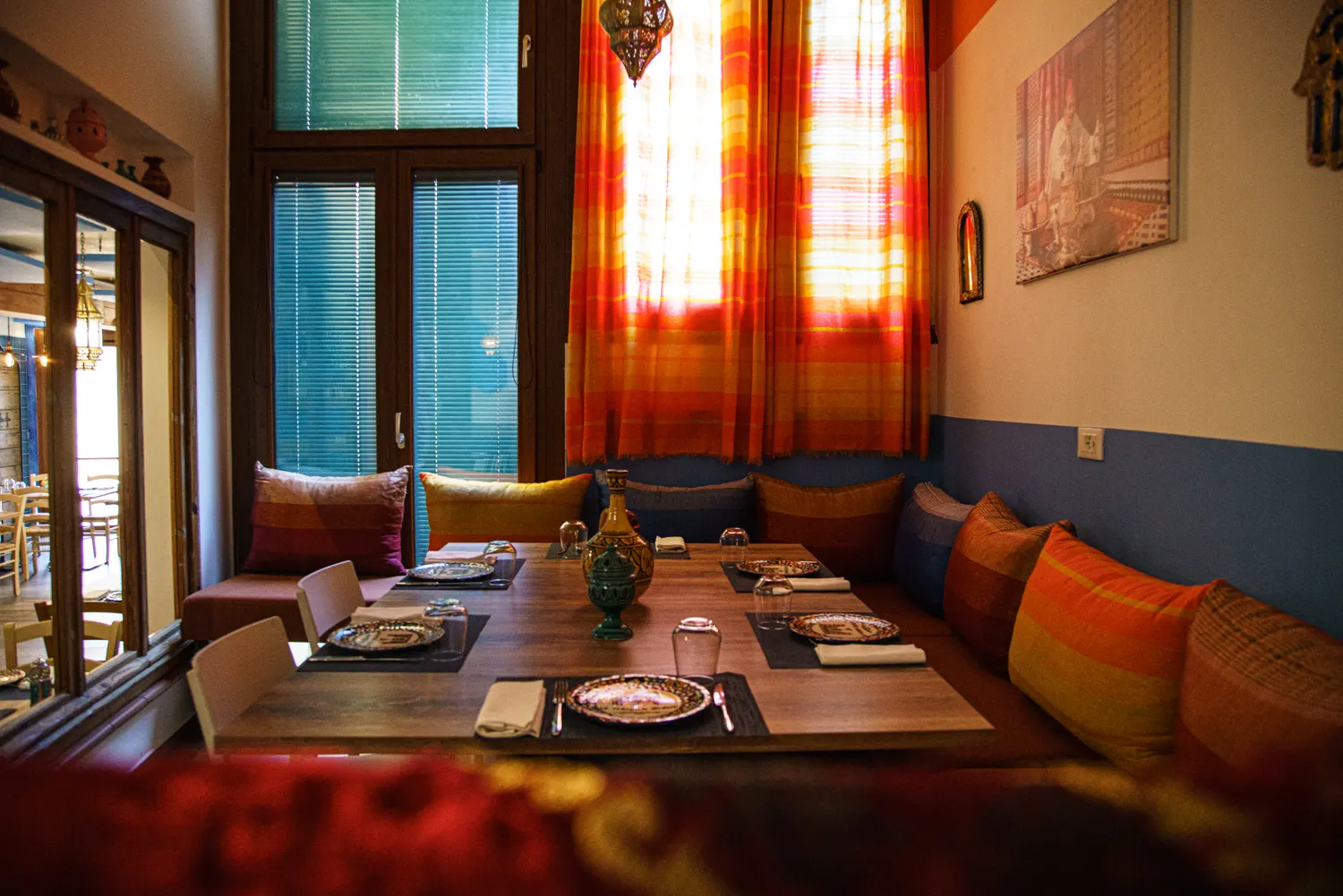 Angolo salotto con cuscini colorati e tavolo apparecchiato