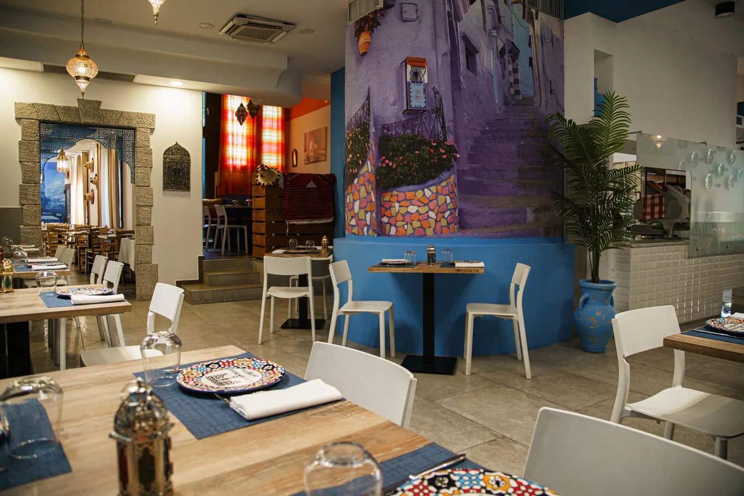 Vista degli interni con murale viola e tavoli apparecchiati