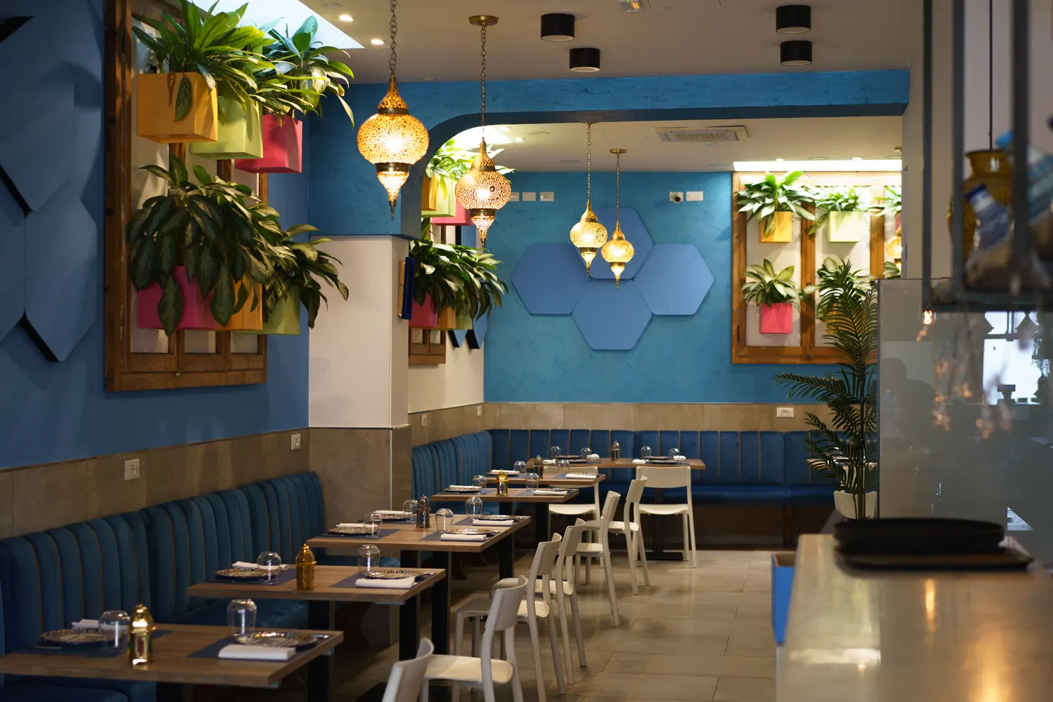 Interni con panche blu, piante decorative e lampade marocchine