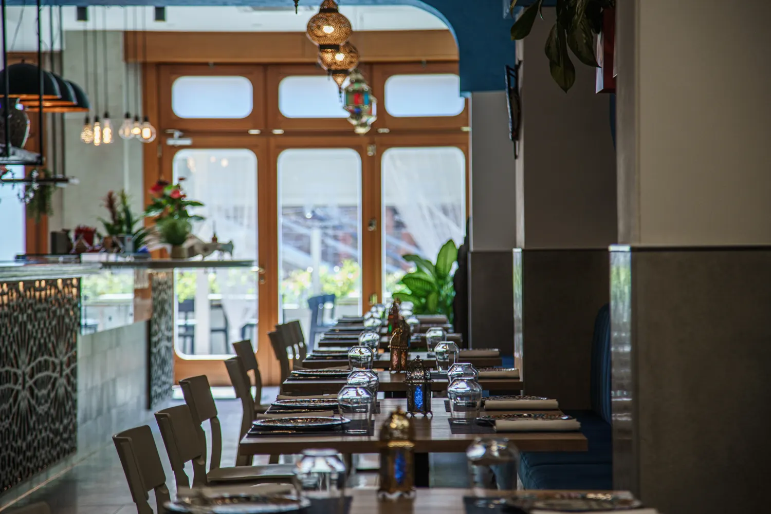 Fila di tavoli apparecchiati verso l'ingresso luminoso